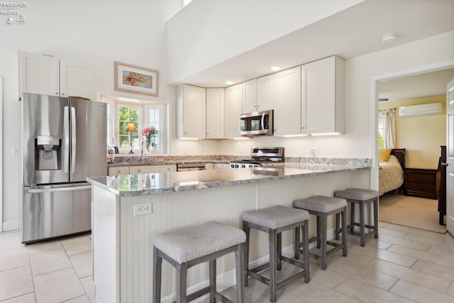 2951 N Chickadee Prt, Clinton, OH 43452 - kitchen featuring a peninsula, white cabinetry, a wall mounted AC, light stone counters, and appliances with stainless steel finishes