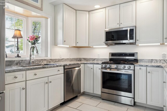 2951 N Chickadee Prt, Clinton, OH 43452 - kitchen with light stone countertops, a sink, stainless steel appliances, white cabinetry, and light tile patterned floors