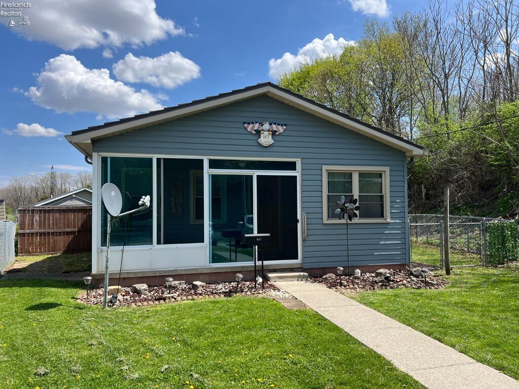 bungalow-style home featuring a front lawn, a sunroom, and fence
