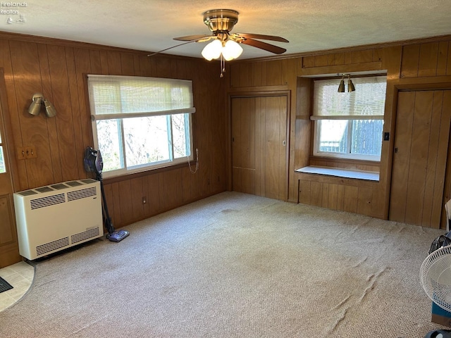 701 Polk St, Sandusky, OH 44870 - unfurnished bedroom with wood walls, heating unit, a ceiling fan, a textured ceiling, and light colored carpet