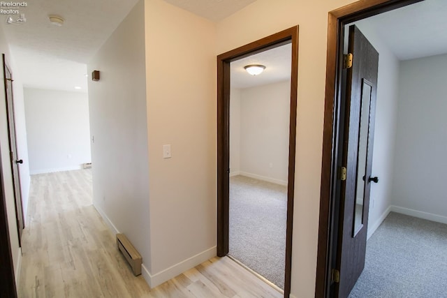 624 Shumaker Dr, Bellevue, OH 44811 - hallway with baseboards, light carpet, a baseboard heating unit, and light wood-style floors