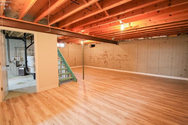 624 Shumaker Dr, Bellevue, OH 44811 - below grade area featuring baseboards, wood finished floors, water heater, and brick wall