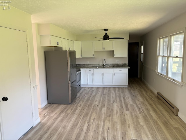 624 Shumaker Dr, Bellevue, OH 44811 - kitchen with white cabinets, ceiling fan, a baseboard heating unit, freestanding refrigerator, and light wood-type flooring