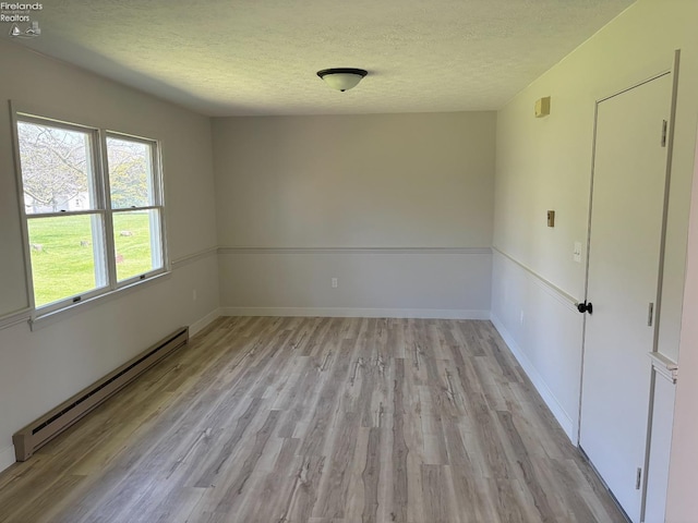 624 Shumaker Dr, Bellevue, OH 44811 - unfurnished room with light wood finished floors, a textured ceiling, baseboards, and a baseboard radiator
