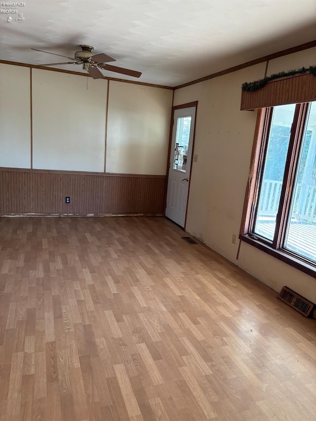 6814 Parker Rd, Castalia, OH 44824 - unfurnished room featuring light wood finished floors, visible vents, ceiling fan, and wainscoting