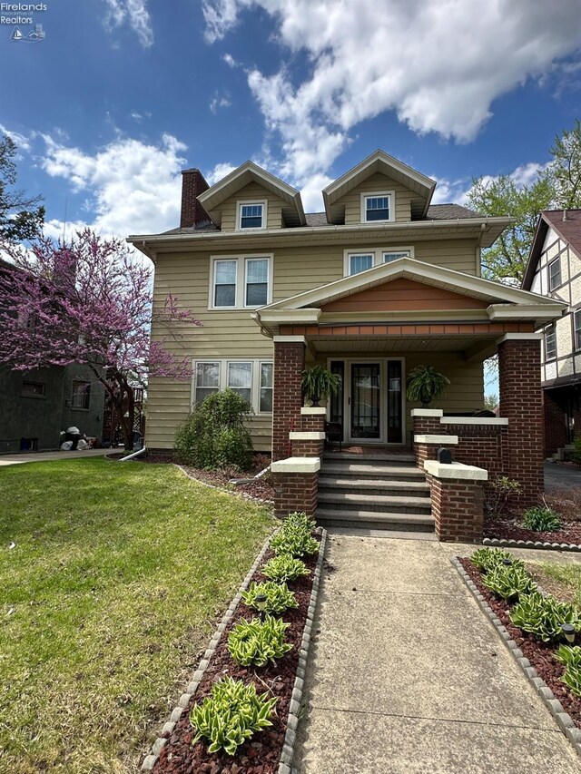 123 E Main, Norwalk, OH 44857 - view of front of house with covered porch, brick siding, a chimney, and a front yard