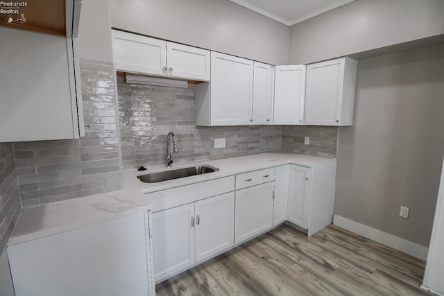 2615 Columbus Ave, Sandusky, OH 44870 - kitchen featuring white cabinetry, light wood finished floors, decorative backsplash, and a sink