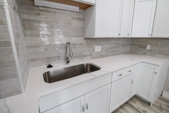 2615 Columbus Ave, Sandusky, OH 44870 - kitchen featuring white cabinetry, tasteful backsplash, a sink, light stone countertops, and light wood finished floors