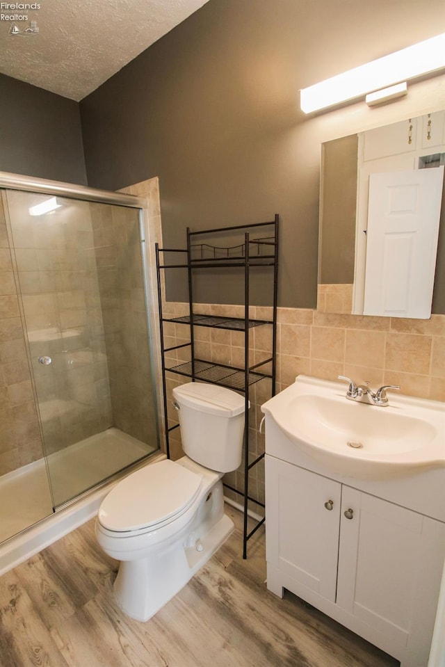 2615 Columbus Ave, Sandusky, OH 44870 - bathroom featuring vanity, toilet, a stall shower, a textured ceiling, and wood finished floors