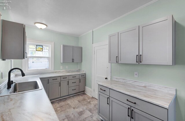 1507 S Lakeview Blvd, Lorain, OH 44052 - kitchen with a sink, stone finish flooring, light countertops, ornamental molding, and gray cabinetry