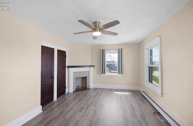 1507 S Lakeview Blvd, Lorain, OH 44052 - unfurnished living room with wood finished floors, baseboard heating, a fireplace, baseboards, and a textured ceiling