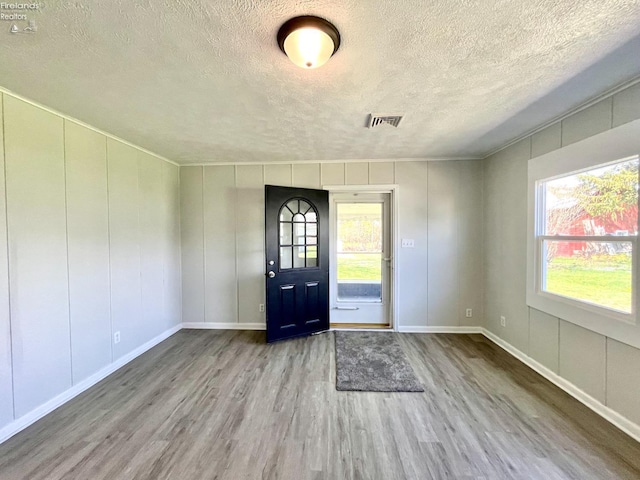 120 Mckim St, Bellevue, OH 44811 - entryway featuring visible vents, wood finished floors, a textured ceiling, and a decorative wall