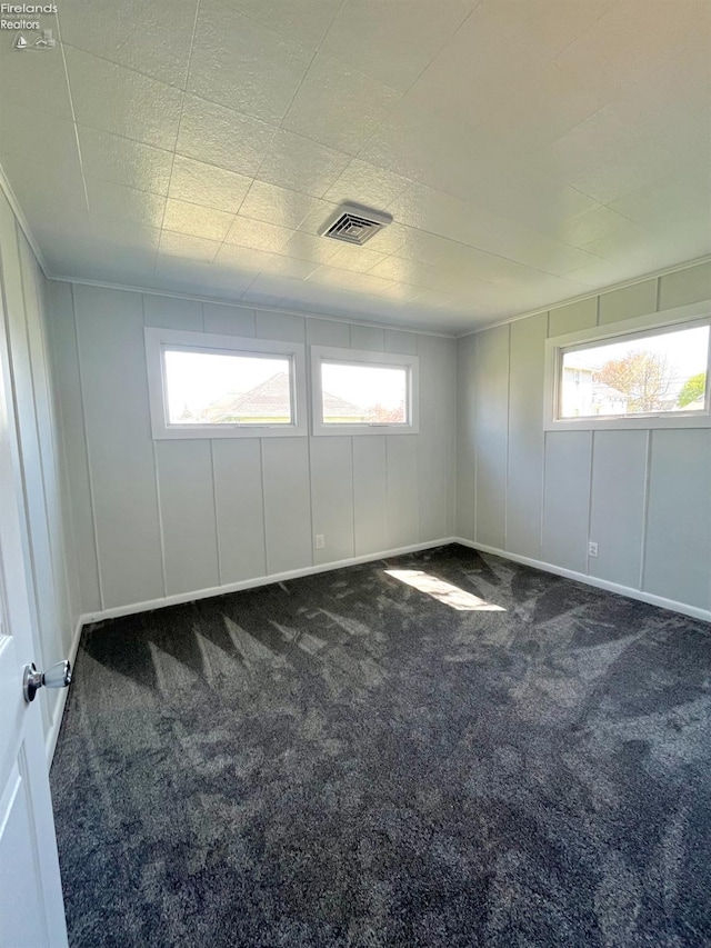 120 Mckim St, Bellevue, OH 44811 - empty room featuring a wealth of natural light, visible vents, a decorative wall, and carpet flooring