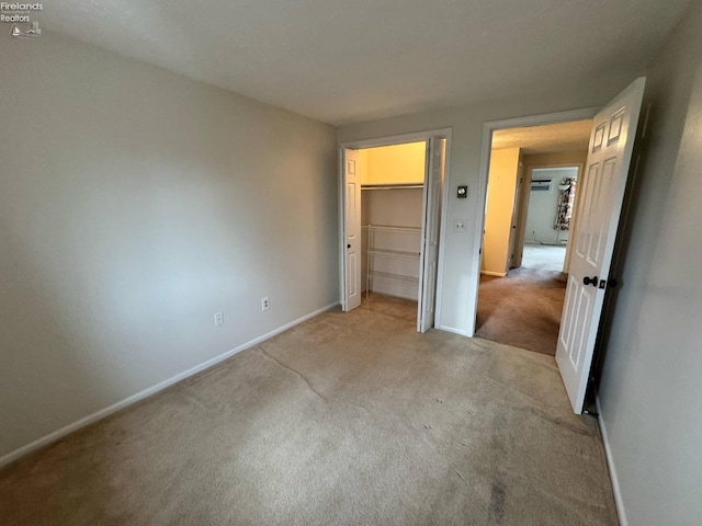 unfurnished bedroom featuring baseboards, a closet, and light colored carpet