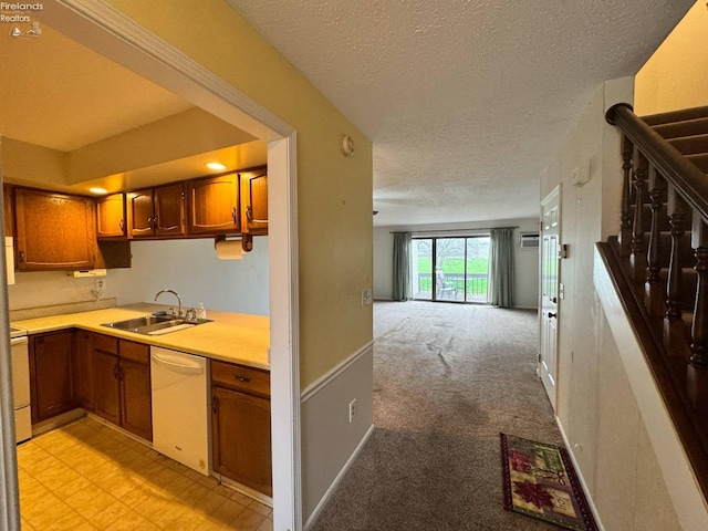 kitchen with light countertops, brown cabinets, dishwasher, a sink, and a textured ceiling