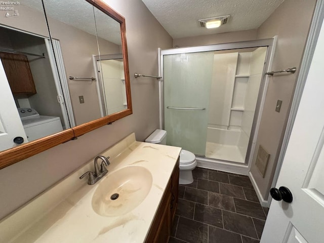 full bathroom with vanity, washer / dryer, toilet, visible vents, and a textured ceiling