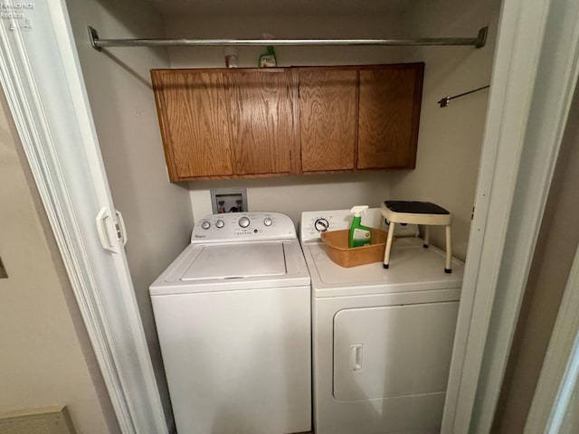 clothes washing area featuring cabinet space and washing machine and clothes dryer