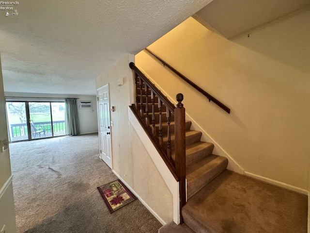 staircase with a textured ceiling, carpet, and baseboards