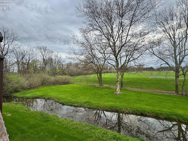 view of property's community with a lawn and fence