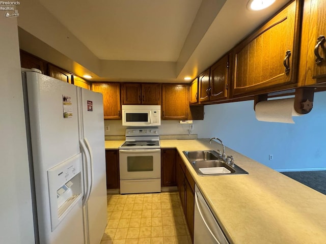 kitchen with white appliances, light countertops, and a sink