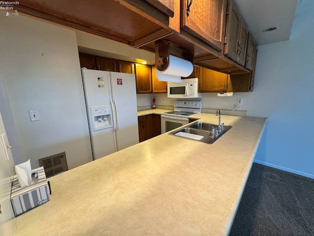 kitchen featuring a sink, visible vents, light countertops, white appliances, and a peninsula