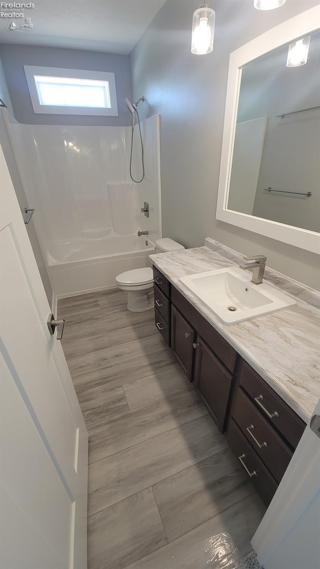 full bath with toilet, wood finished floors, vanity, and  shower combination