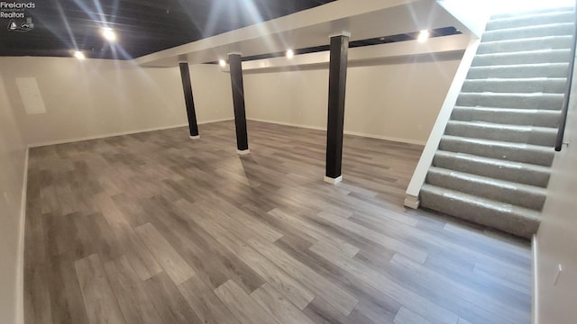 finished below grade area with baseboards and wood finished floors