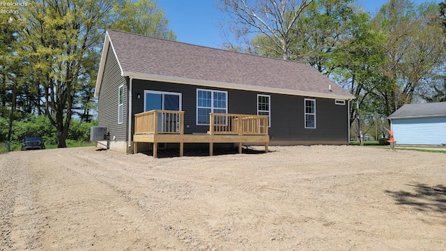 view of front of house with driveway, a deck, central air condition unit, and a shingled roof