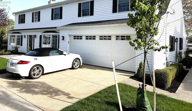 traditional-style house with an attached garage, concrete driveway, and a chimney