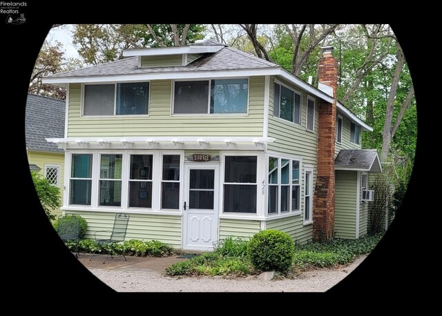 view of side of property with a chimney and a shingled roof