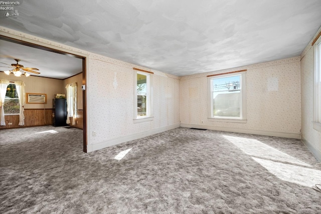 carpeted empty room featuring a ceiling fan, an AC wall unit, and wallpapered walls