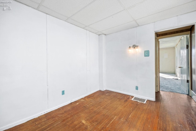 spare room featuring baseboards, visible vents, wood-type flooring, and a paneled ceiling