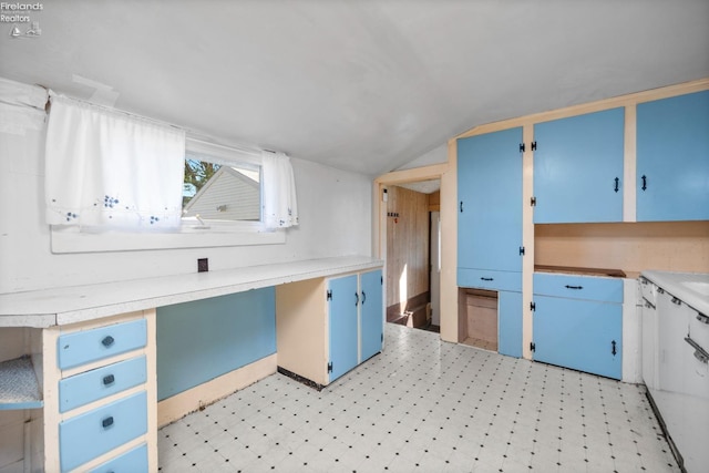 kitchen with light countertops, light floors, vaulted ceiling, and blue cabinets