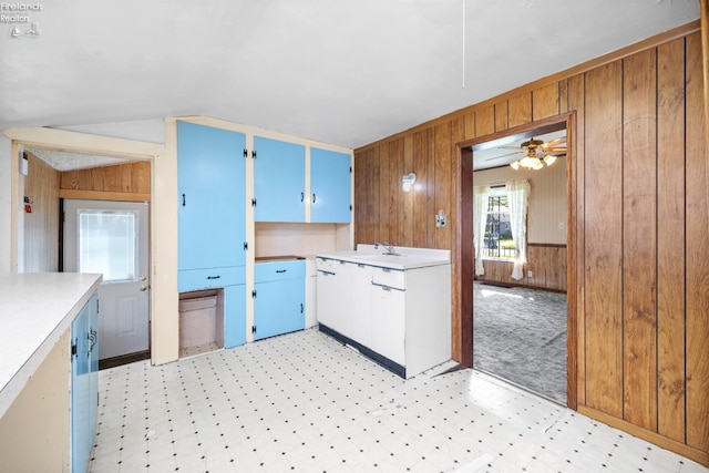 kitchen with wooden walls, a ceiling fan, light floors, and light countertops