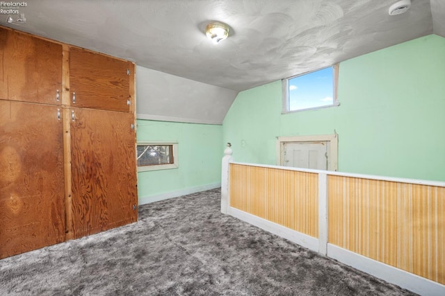 additional living space featuring baseboards, carpet flooring, and vaulted ceiling