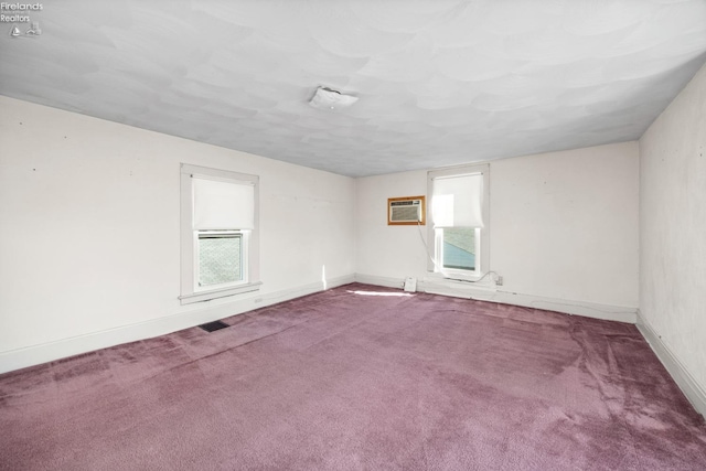 unfurnished room featuring baseboards, carpet flooring, a wall unit AC, and visible vents