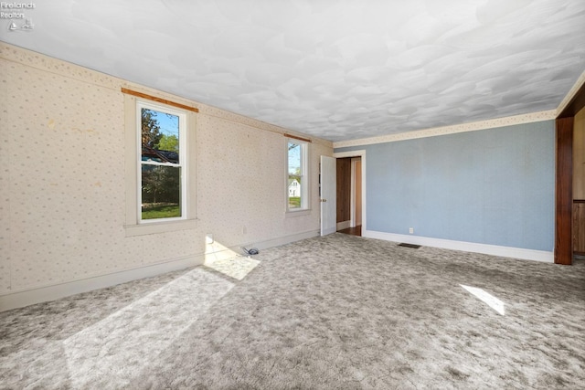 empty room featuring visible vents, carpet, and baseboards