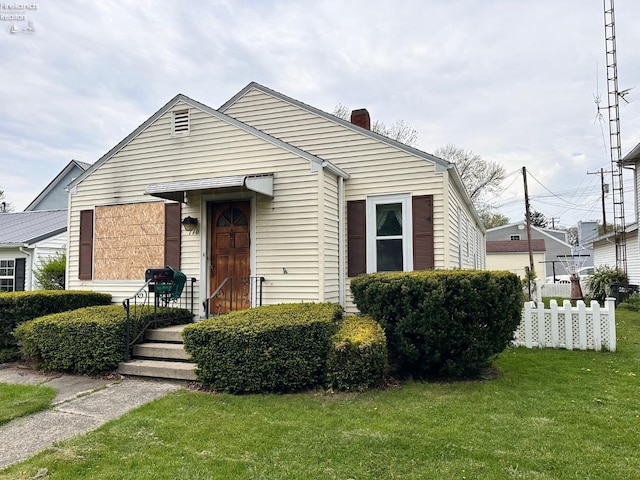 bungalow-style home featuring fence, a chimney, and a front yard