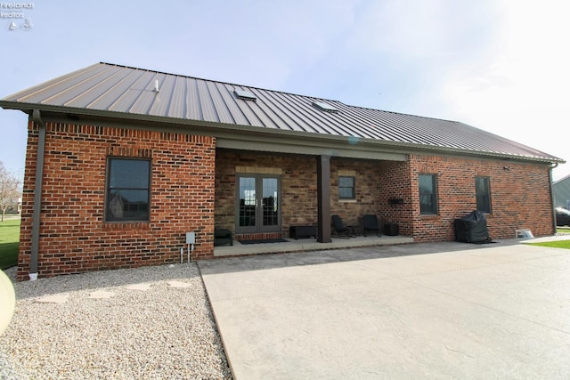 9117 W Mason Rd, Castalia, OH 44824 - back of property with brick siding, a patio area, metal roof, and french doors