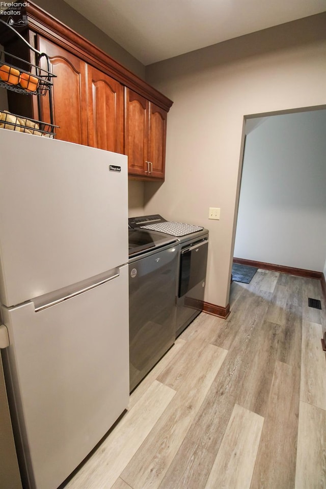 9117 W Mason Rd, Castalia, OH 44824 - laundry area with washing machine and clothes dryer, light wood-style floors, cabinet space, and baseboards