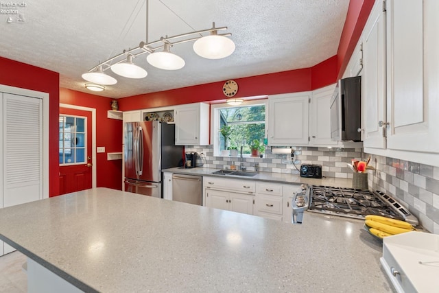 11595 Gore Orphanage Rd, Wakeman, OH 44889 - kitchen featuring stainless steel appliances, a sink, a textured ceiling, white cabinetry, and decorative backsplash