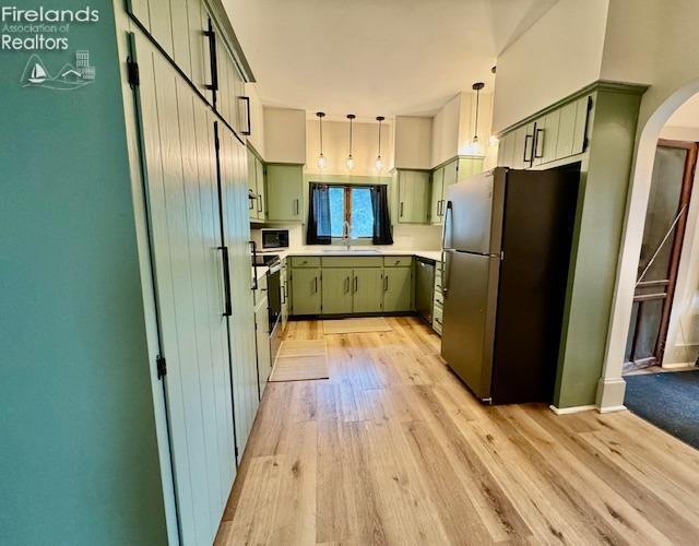 1026 Claremont Ave, Ashland, OH 44805 - kitchen with freestanding refrigerator, green cabinets, arched walkways, and light wood-style flooring