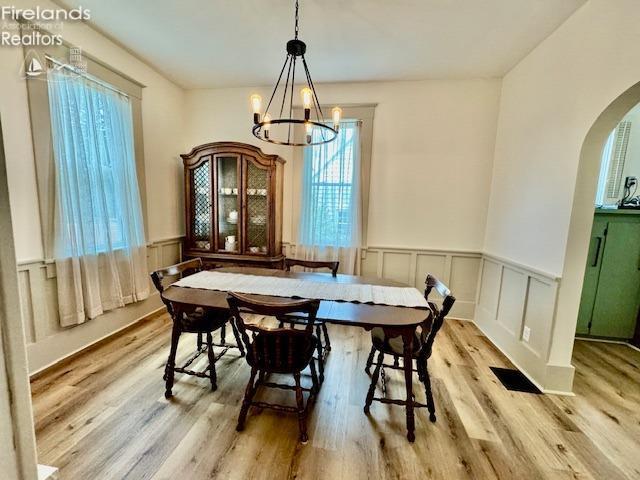 1026 Claremont Ave, Ashland, OH 44805 - dining room featuring arched walkways, a chandelier, wainscoting, wood finished floors, and a decorative wall