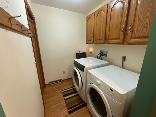 clothes washing area with separate washer and dryer, cabinet space, visible vents, baseboards, and light wood-style floors