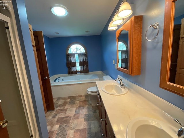 full bathroom with double vanity, a bath, stone finish flooring, and a sink