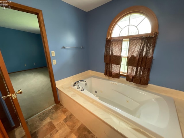 full bathroom featuring a tub with jets and stone finish flooring