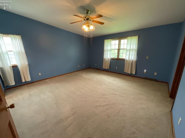 carpeted spare room featuring ceiling fan, baseboards, and visible vents