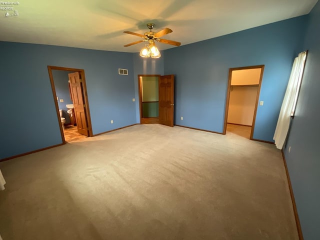 unfurnished bedroom with light colored carpet, visible vents, ceiling fan, a spacious closet, and baseboards