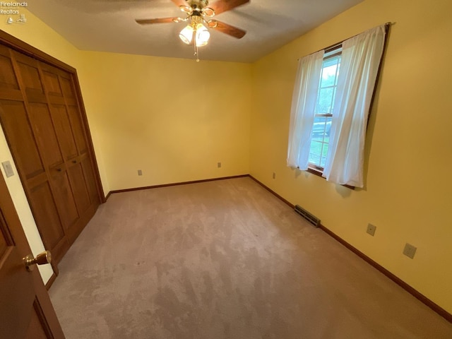 unfurnished bedroom with a closet, visible vents, baseboards, ceiling fan, and light carpet