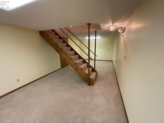 finished below grade area with baseboards, stairway, and light colored carpet